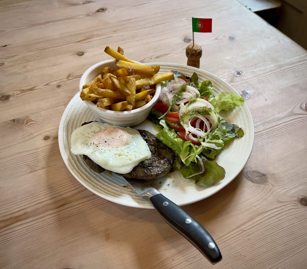Bistoque, homemade chips and a salad garnished with pesto, next to a Portuguese cocktail stick flag.