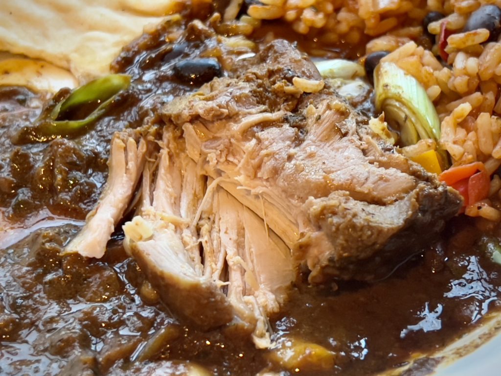 A cross-section of the brown stew chicken, showing its tender texture.