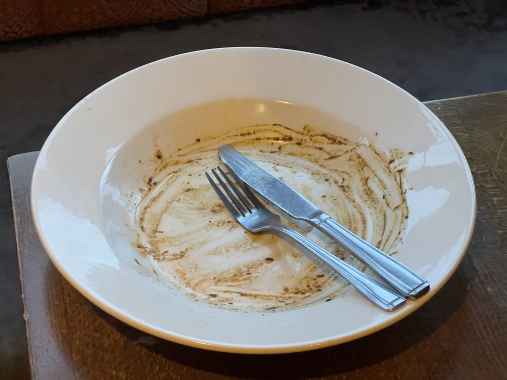 An empty plate with a knife and fork positioned to show one has finished eating.