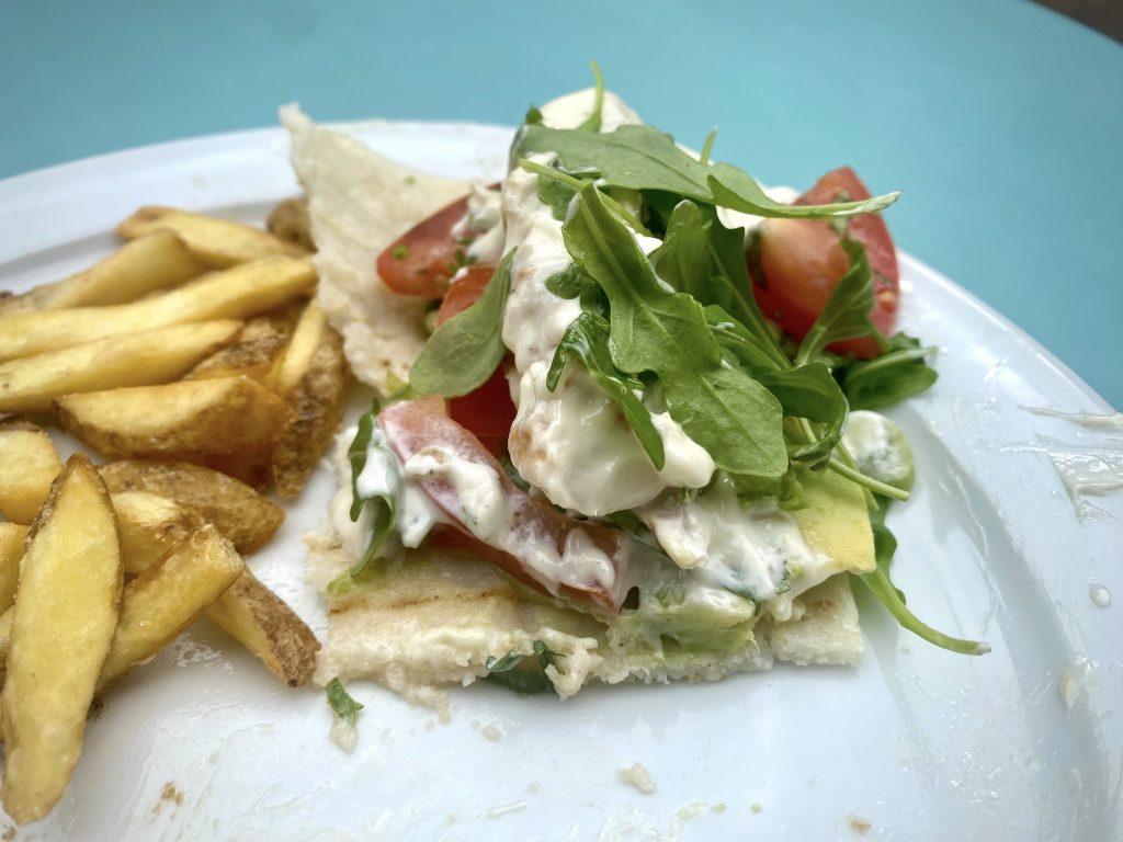 The cross-section of a chicken, aioli, avocado, rocket and tomato arepa.
