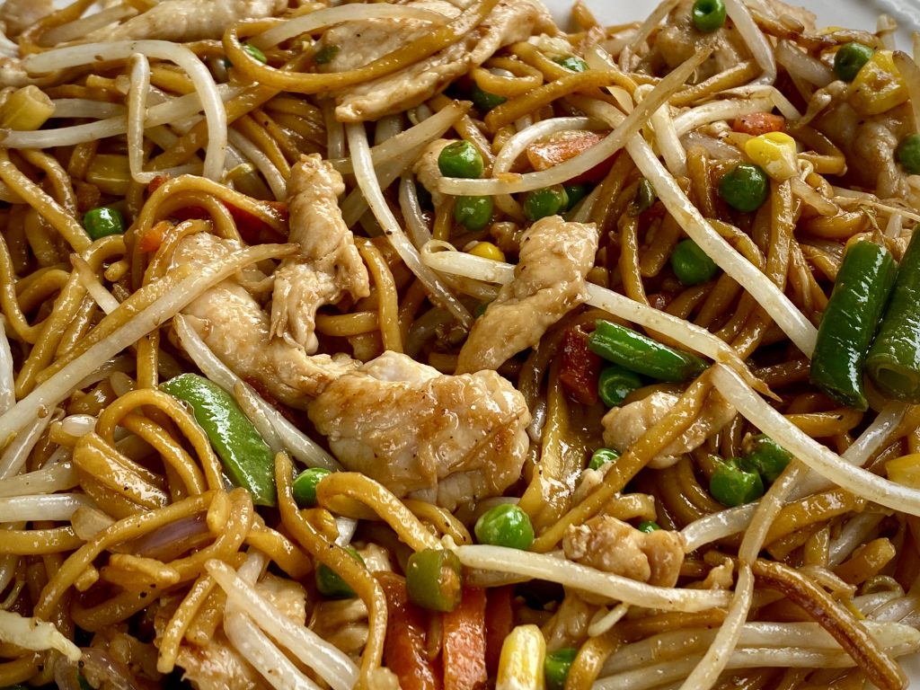 Close-up of a chicken chow mein, showing the dish's variety of vegetables, noodles and chicken.