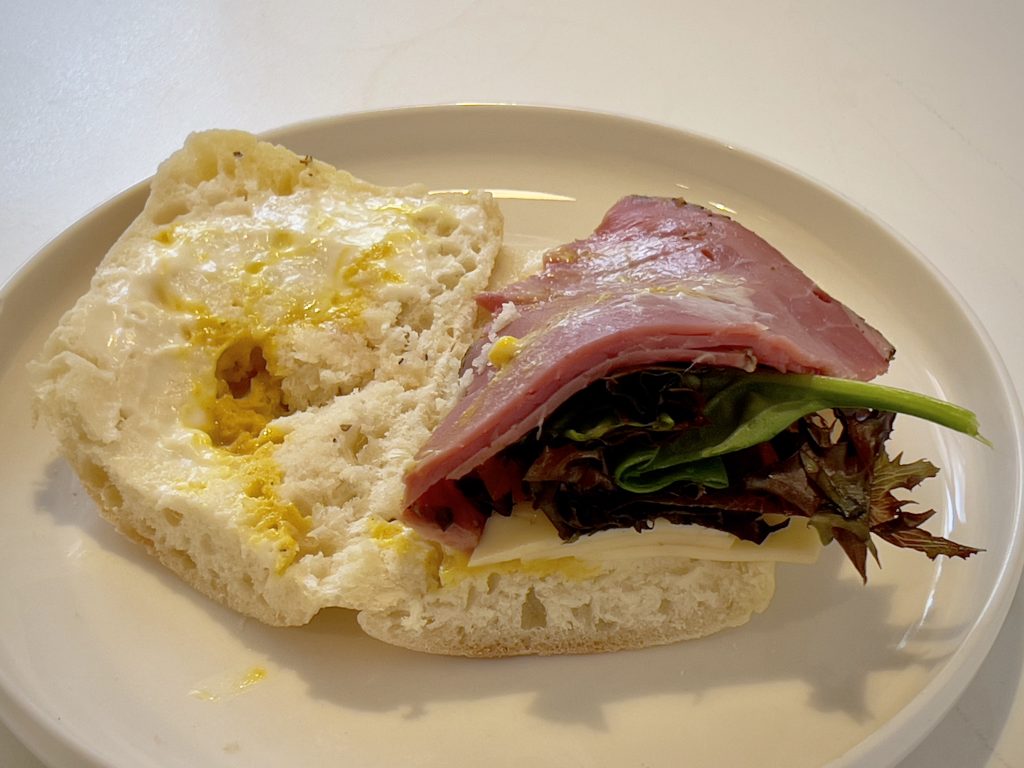A deconstructed New York Deli sandwich, showing, with the two halves of bread separated to make the fillings visible.