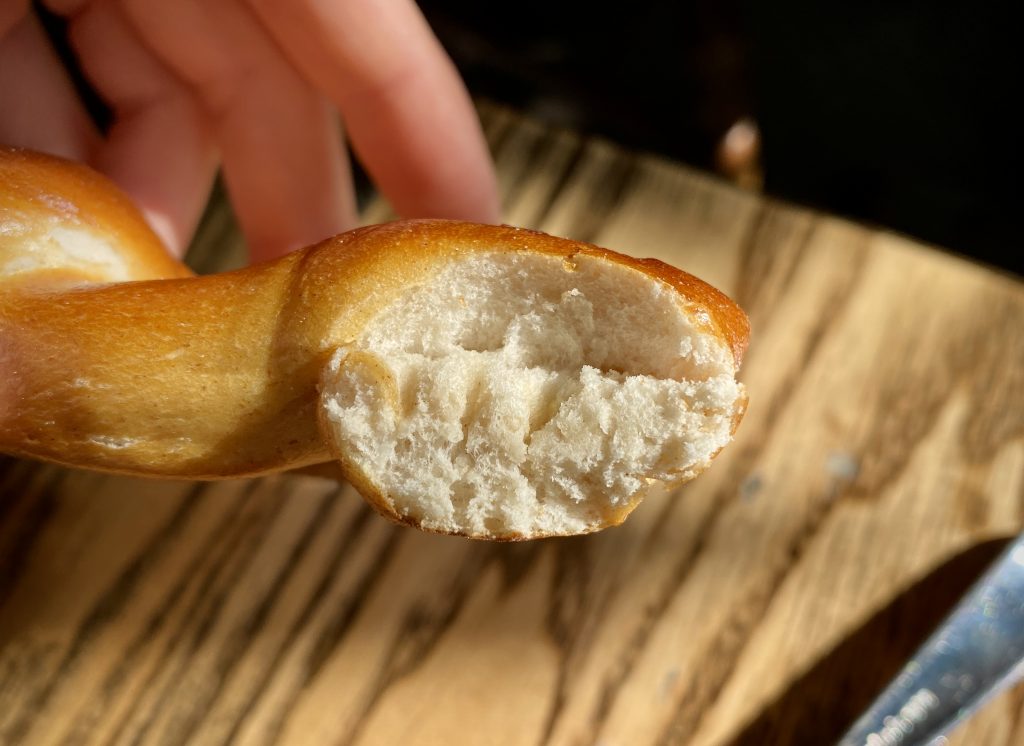 A cross-section of a German Pretzel, held up to the camera for a close look at the bread's texture.