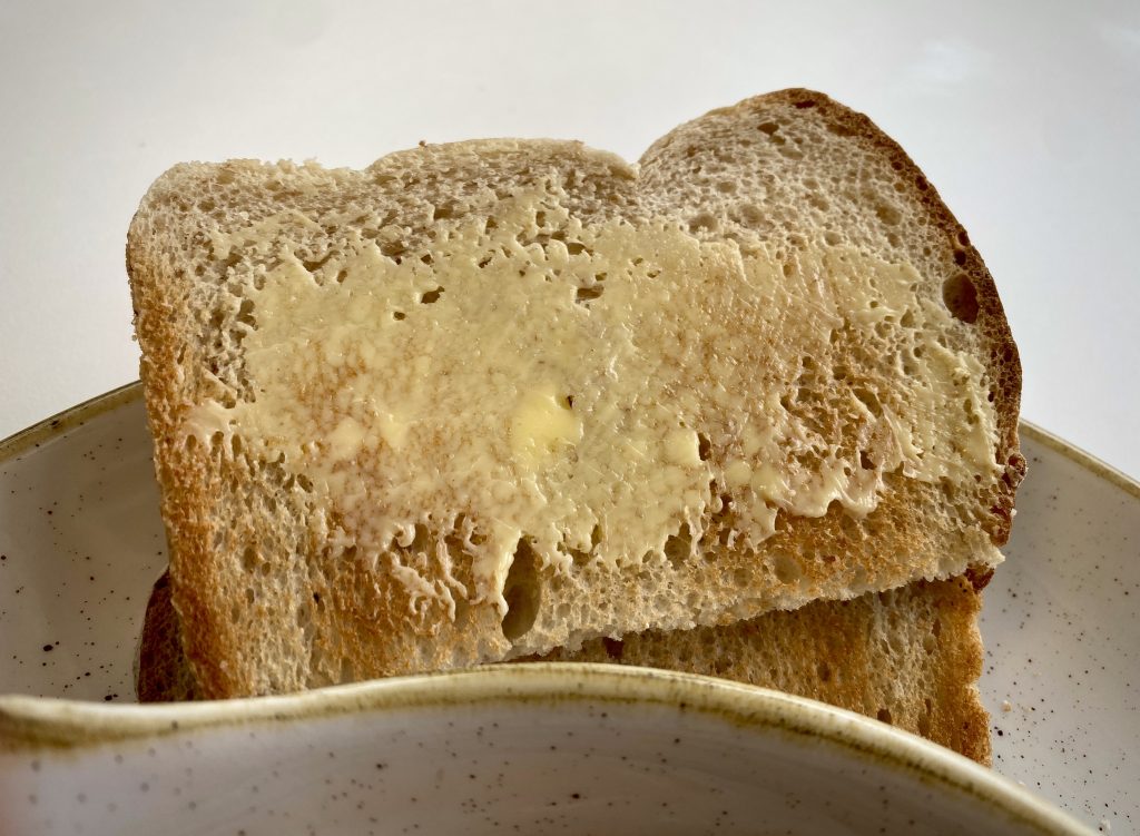 A close-up of two buttered slices of toast stacked on a plate.