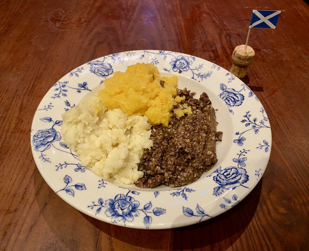 A plate of haggis, neeps and tatties, next to a Scottish cocktail stick flag.